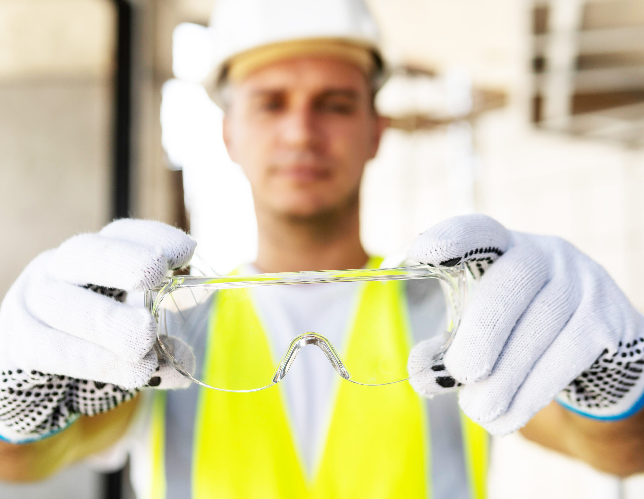Mann zeigt seine Schutzbrille und hat einen Schutzhelm auf