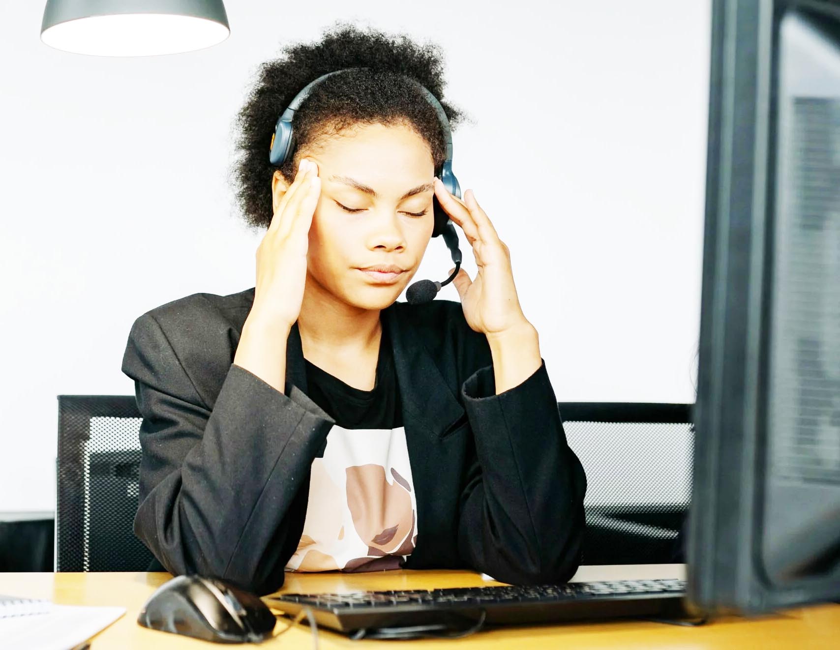 Frau sitzt mit Headset vor dem Computer