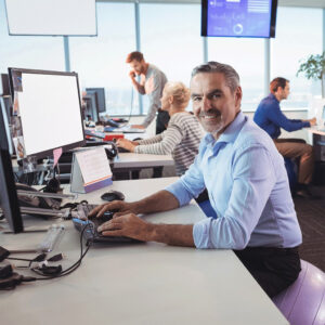 Mann sitzt am Arbeitsplatz im Großraumbüro