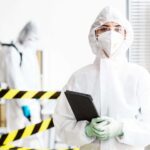 Frau im Schutzanzug mit Tablet